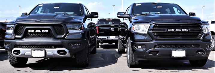 Two black RAM trucks parked side by side in a lot, showcasing their front designs.