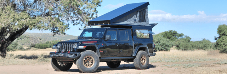 Off-road vehicle with rooftop tent in a scenic outdoor landscape.