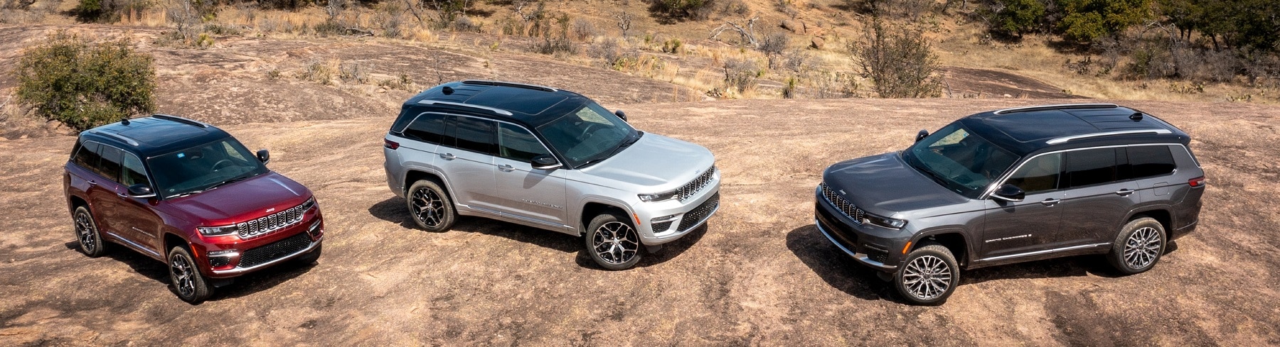 Three SUVs parked on a rocky terrain, showcasing their robust design against a dry, natural landscape.