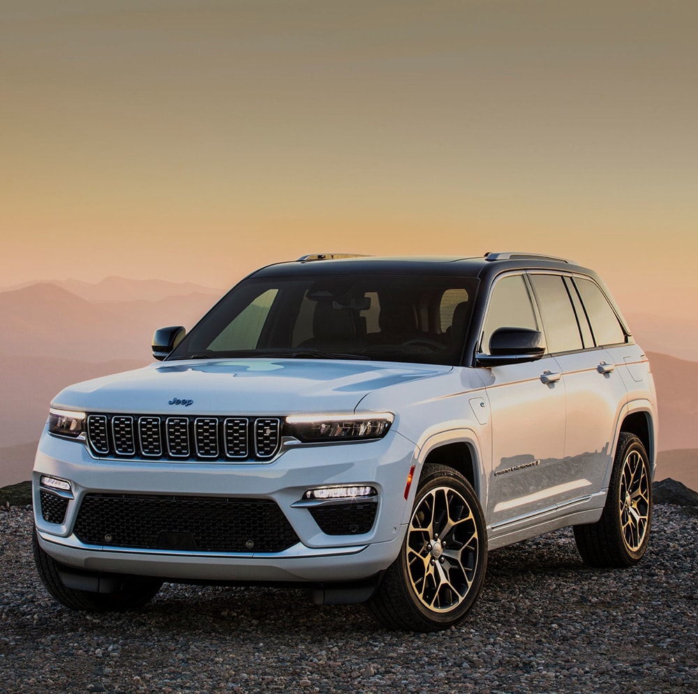 White SUV parked on gravel road at sunset, featuring rugged design and elegant alloy wheels.