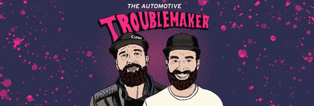 Illustrated poster of two bearded men with caps, titled "The Automotive Troublemaker."