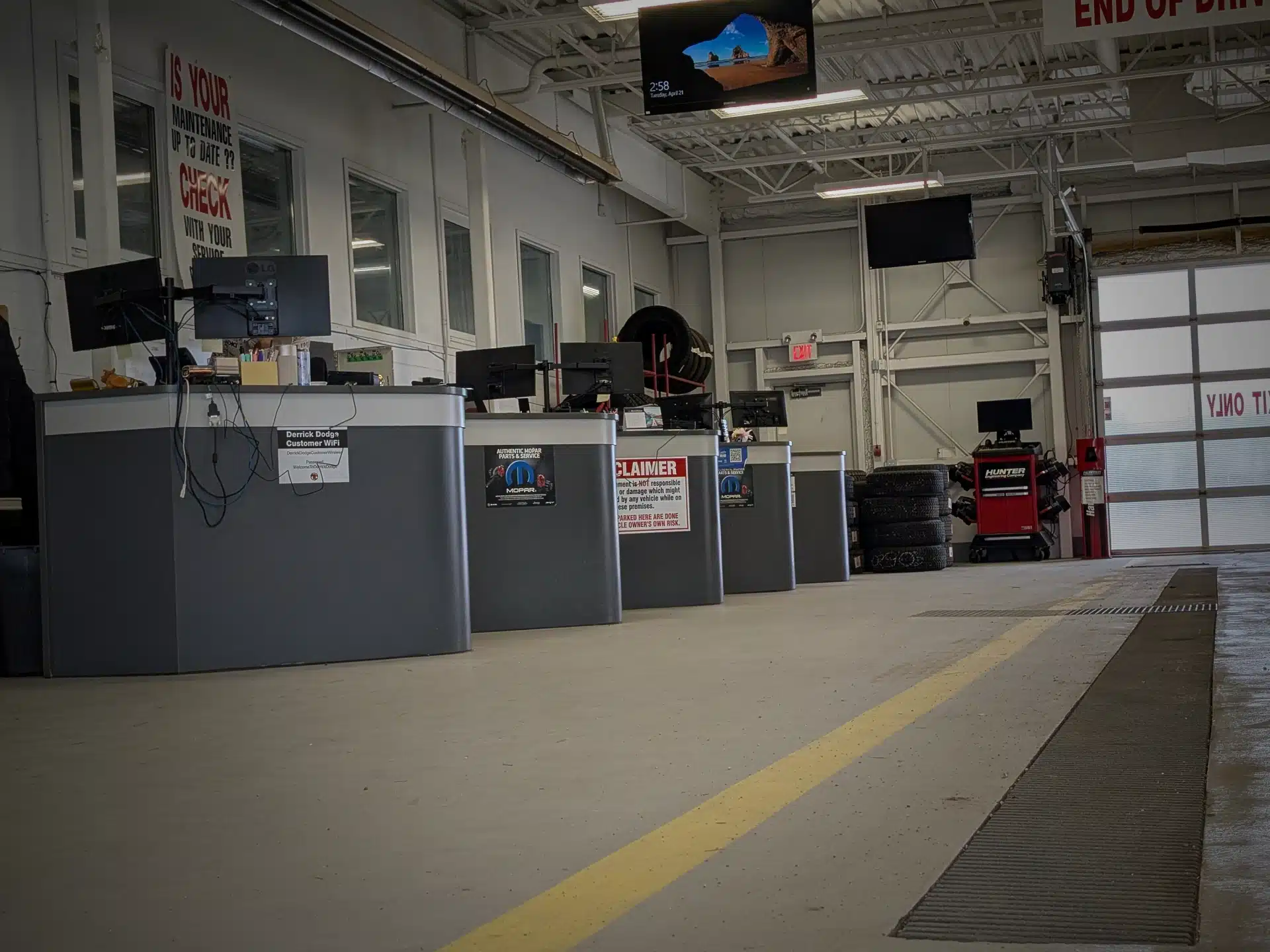 Auto service center with desks, monitors, tire stacks, and maintenance signage.