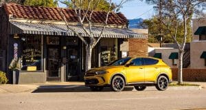 Yellow SUV parked in front of a vintage barbershop under a striped awning on a sunny day.